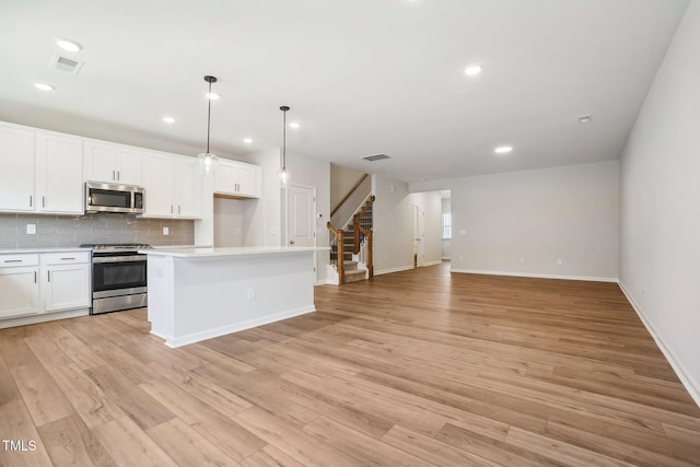 kitchen featuring light hardwood / wood-style flooring, hanging light fixtures, appliances with stainless steel finishes, white cabinetry, and a center island