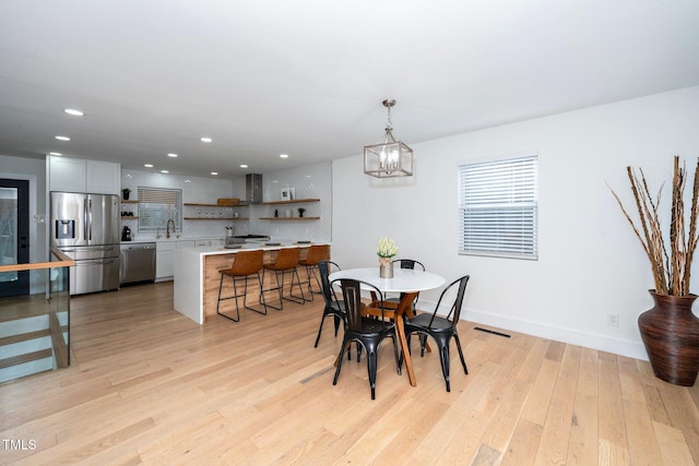 dining space with sink, a chandelier, and light hardwood / wood-style floors