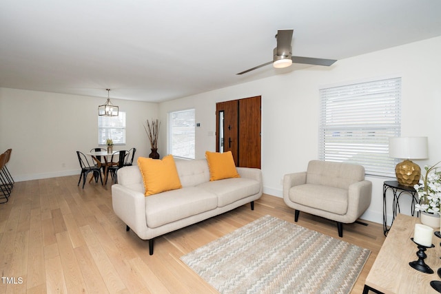 living room with ceiling fan with notable chandelier and light wood-type flooring