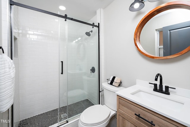 bathroom featuring vanity, a shower with door, and toilet