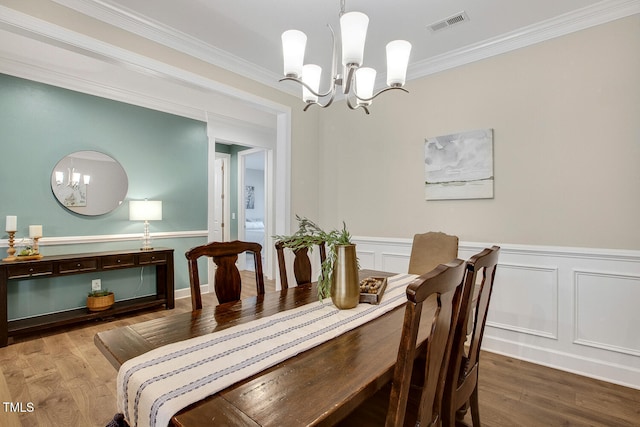 dining room with crown molding, a notable chandelier, and hardwood / wood-style flooring