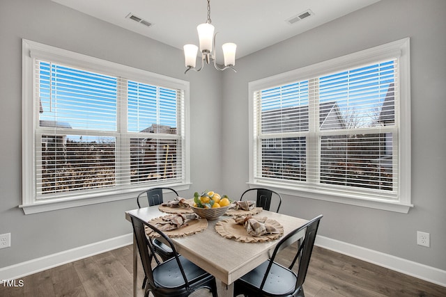 dining space with dark hardwood / wood-style floors and an inviting chandelier