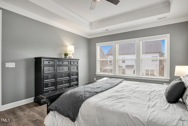 bedroom with crown molding, dark hardwood / wood-style flooring, and a raised ceiling