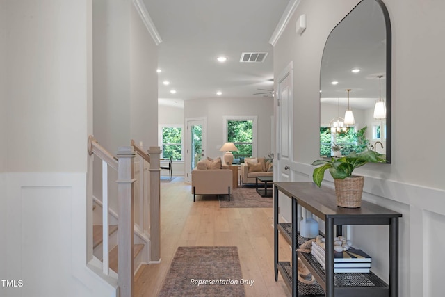 corridor with ornamental molding and light hardwood / wood-style floors