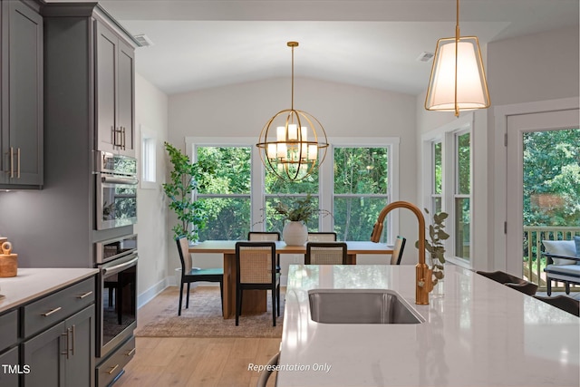 kitchen featuring decorative light fixtures, gray cabinets, lofted ceiling, and an inviting chandelier