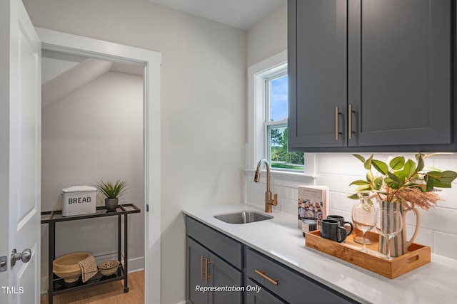 bar featuring light wood-style floors, a sink, and backsplash