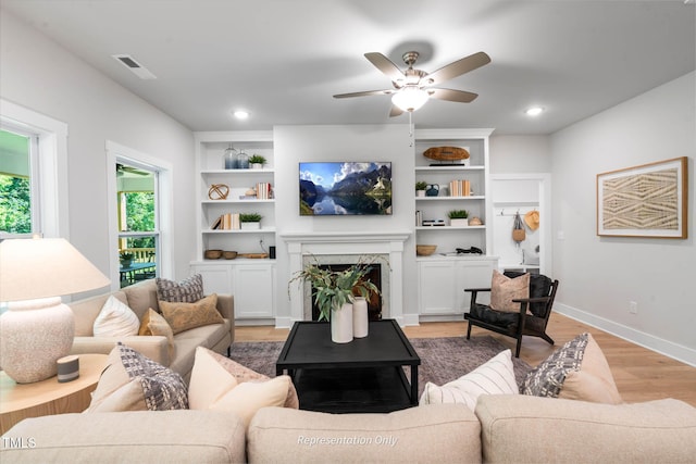 living room featuring a fireplace, recessed lighting, visible vents, light wood-type flooring, and baseboards