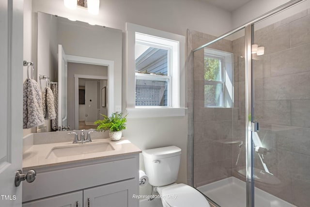 bathroom featuring a shower with shower door, vanity, and toilet