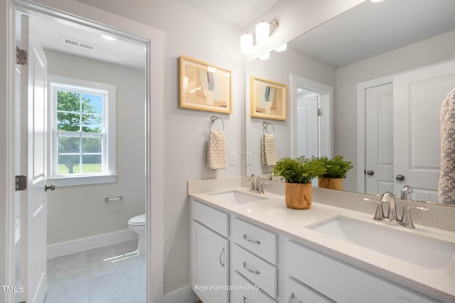 bathroom with toilet, double vanity, a sink, and visible vents