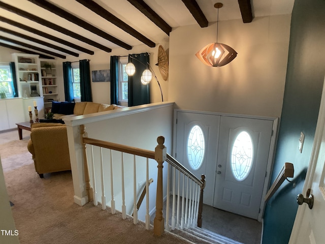 foyer entrance with light colored carpet and vaulted ceiling with beams