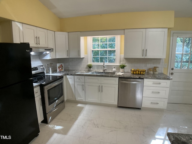 kitchen with white cabinets, stainless steel appliances, dark stone countertops, tasteful backsplash, and sink