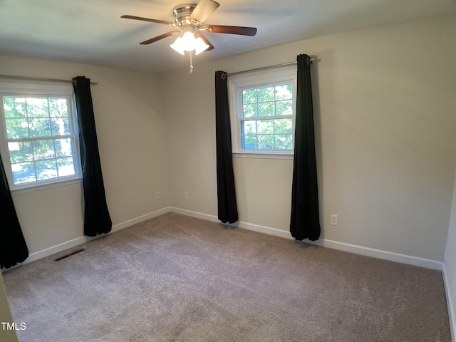 carpeted spare room with ceiling fan and plenty of natural light