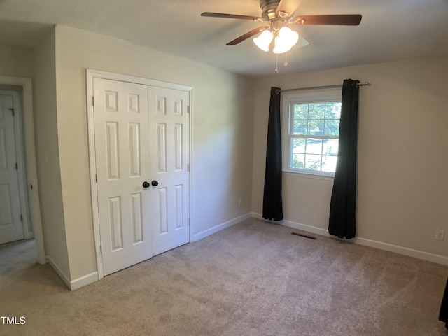 unfurnished bedroom with ceiling fan, light colored carpet, and a closet