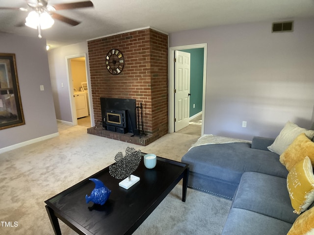 carpeted living room featuring ceiling fan, washer and dryer, and a wood stove