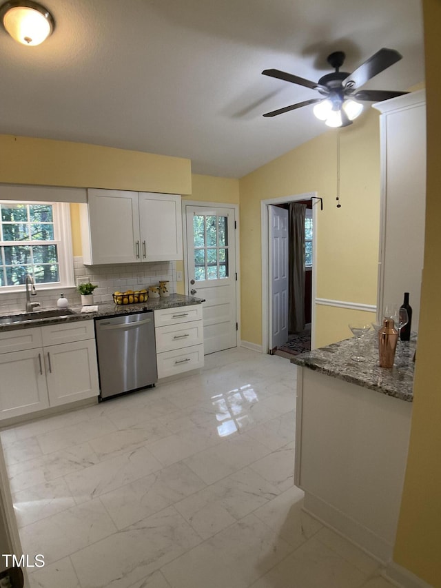 kitchen featuring white cabinetry, decorative backsplash, vaulted ceiling, stainless steel dishwasher, and sink