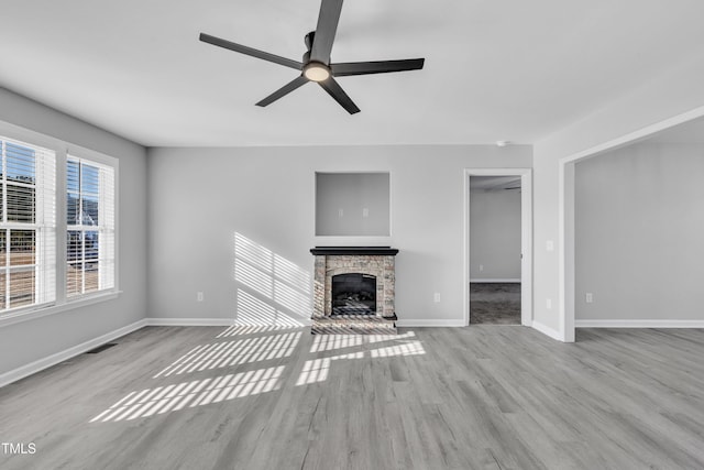 unfurnished living room featuring ceiling fan, a fireplace, and light hardwood / wood-style flooring