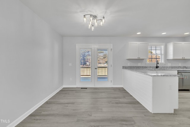 kitchen featuring white cabinetry, dishwasher, french doors, light stone counters, and sink