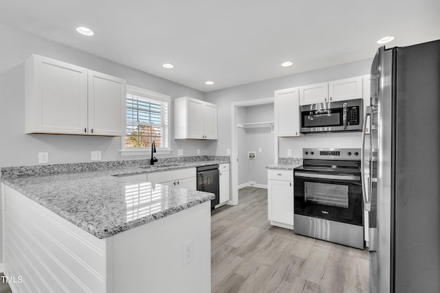 kitchen with light stone counters, kitchen peninsula, white cabinets, and stainless steel appliances