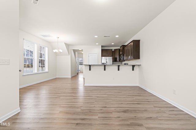 unfurnished living room with an inviting chandelier and light hardwood / wood-style flooring