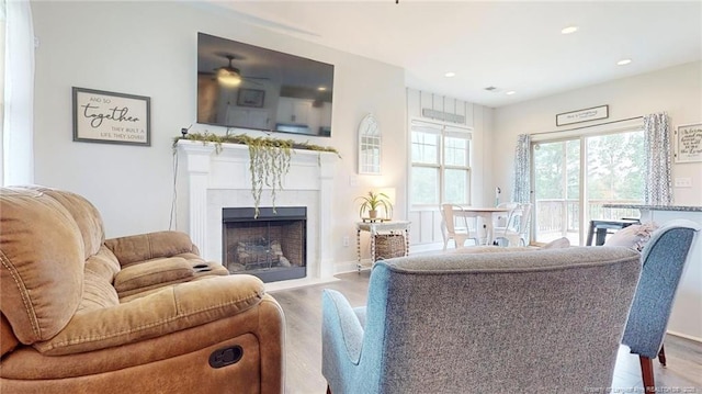 living room featuring light wood-type flooring, ceiling fan, and a fireplace