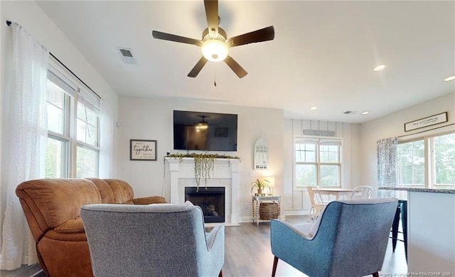 living room with ceiling fan, a wealth of natural light, and light wood-type flooring