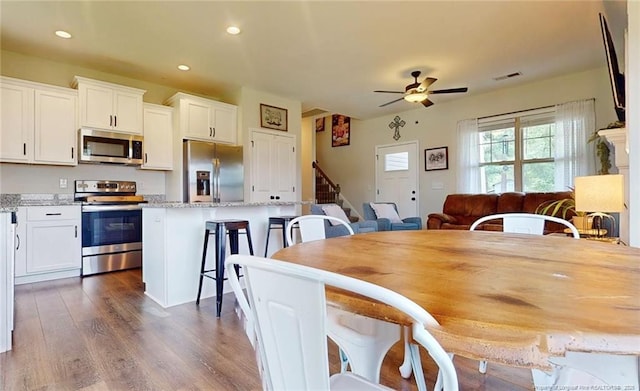 dining space with ceiling fan and dark hardwood / wood-style flooring