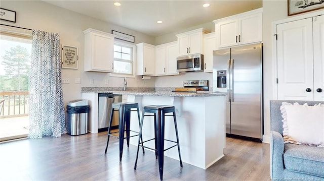 kitchen featuring a breakfast bar area, appliances with stainless steel finishes, white cabinetry, and a center island