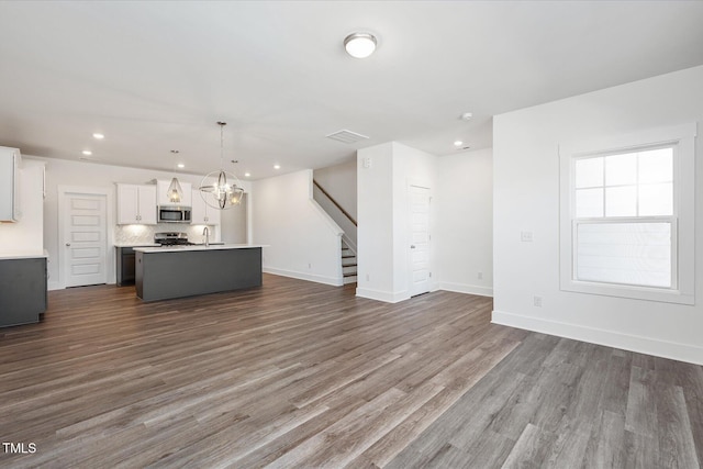 unfurnished living room with hardwood / wood-style flooring, sink, and a notable chandelier