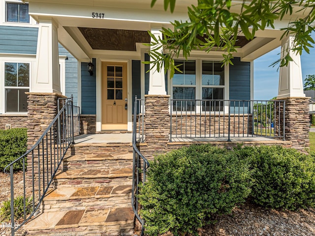 property entrance with a porch and stone siding