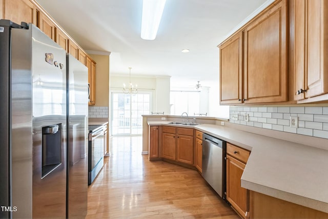 kitchen featuring pendant lighting, appliances with stainless steel finishes, light hardwood / wood-style floors, sink, and kitchen peninsula