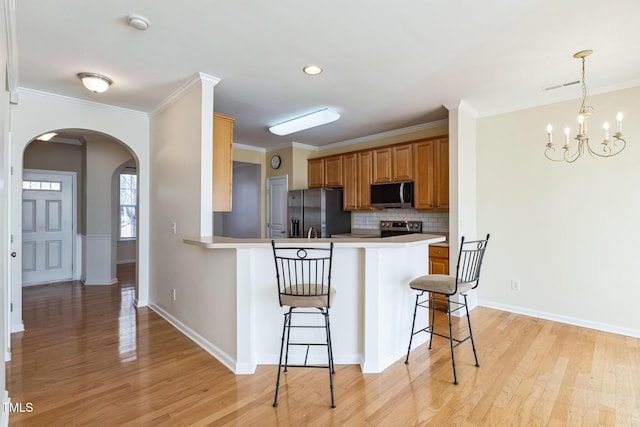 kitchen featuring tasteful backsplash, light wood-type flooring, kitchen peninsula, a breakfast bar, and stainless steel appliances