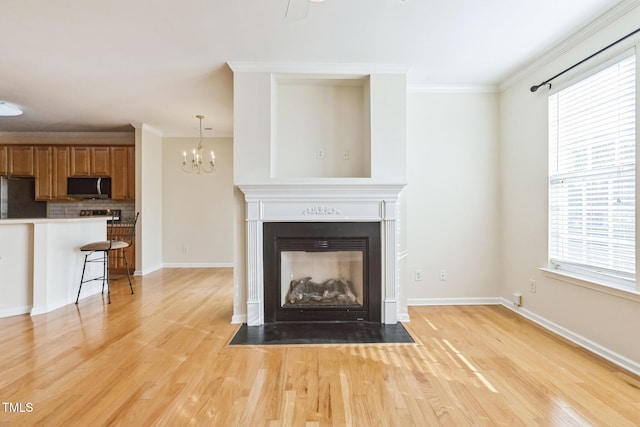 unfurnished living room featuring crown molding, a multi sided fireplace, light hardwood / wood-style flooring, and an inviting chandelier