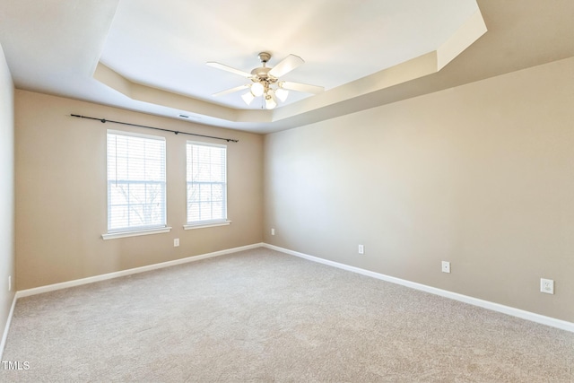 spare room featuring ceiling fan, carpet floors, and a tray ceiling