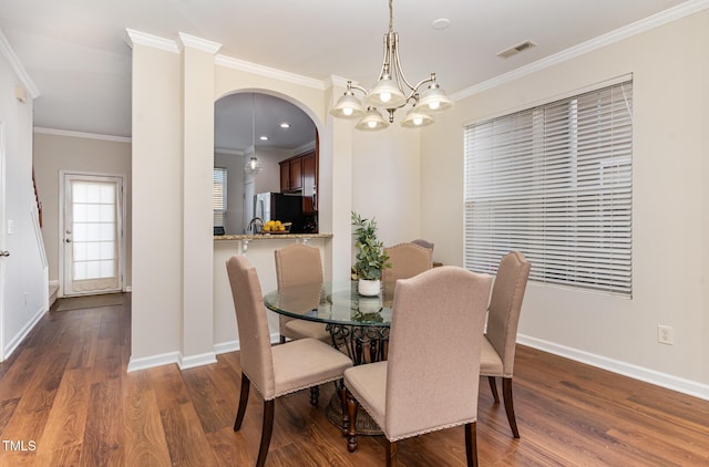 dining area with an inviting chandelier, dark hardwood / wood-style flooring, and crown molding