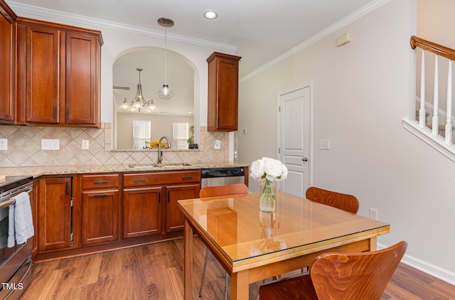 kitchen featuring sink, crown molding, hanging light fixtures, light stone countertops, and appliances with stainless steel finishes