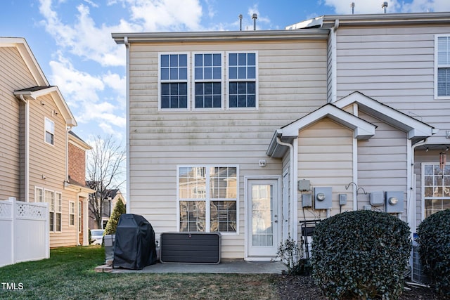 back of property with a lawn and a patio