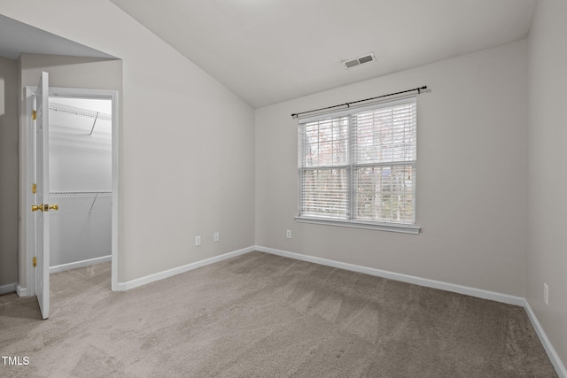 carpeted empty room featuring vaulted ceiling