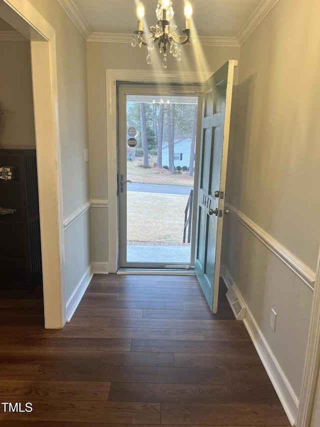 doorway to outside featuring dark hardwood / wood-style flooring, ornamental molding, and a notable chandelier