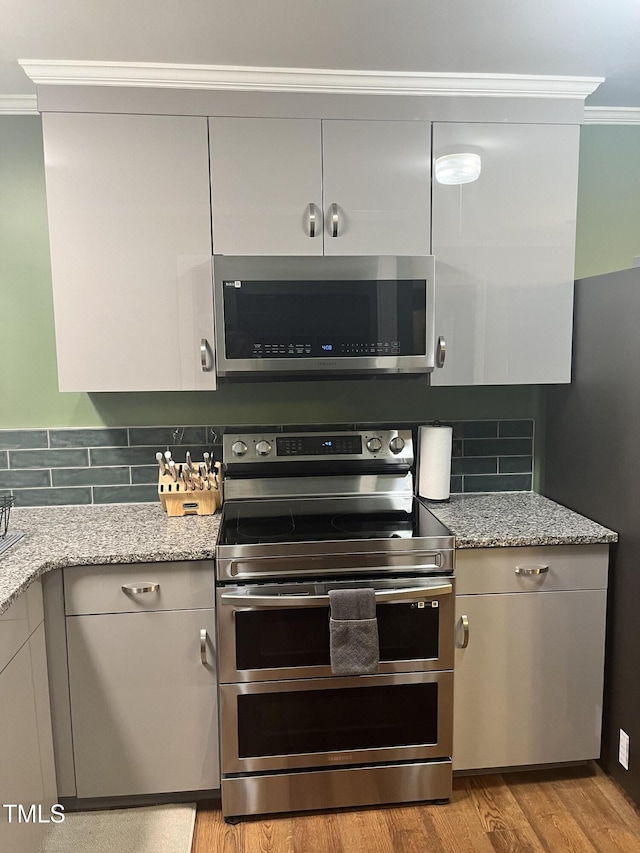 kitchen with light stone counters, backsplash, and stainless steel appliances