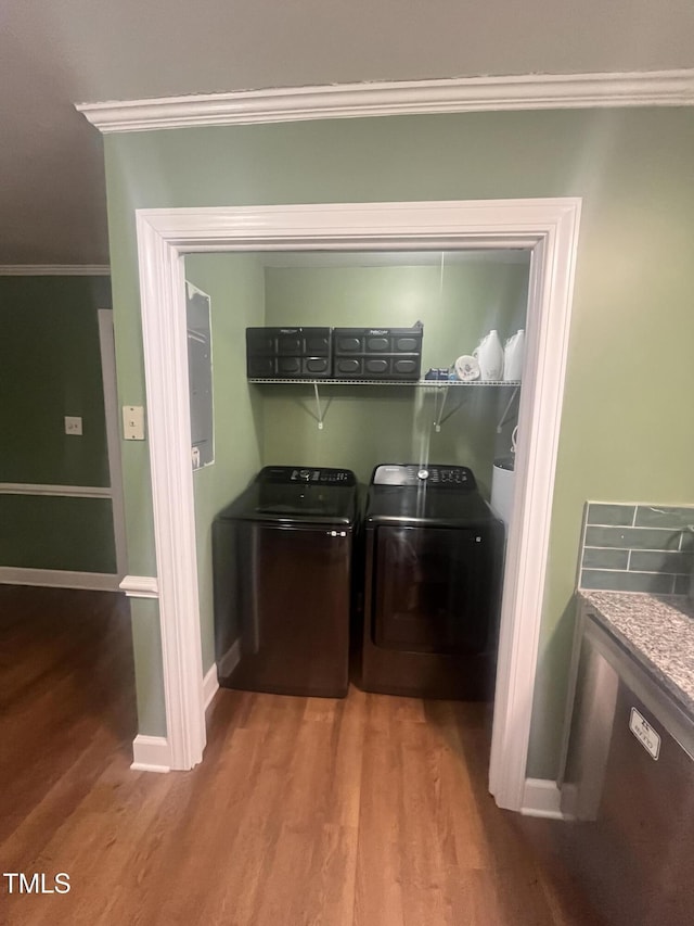 laundry room with washer and clothes dryer, ornamental molding, and hardwood / wood-style flooring