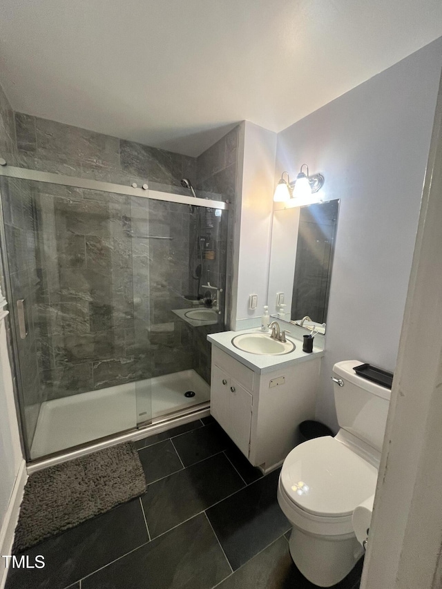 bathroom featuring a shower with shower door, toilet, vanity, and tile patterned flooring