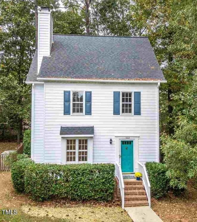 view of front of house featuring a shingled roof, entry steps, and a chimney