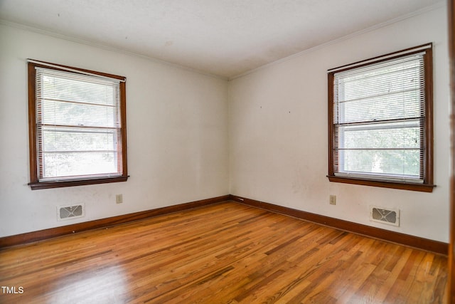 spare room featuring wood-type flooring, plenty of natural light, and crown molding