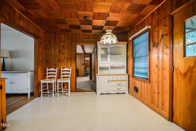 unfurnished dining area featuring wood ceiling and wooden walls