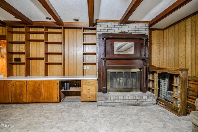 unfurnished living room with wood walls, a brick fireplace, a textured ceiling, and beam ceiling