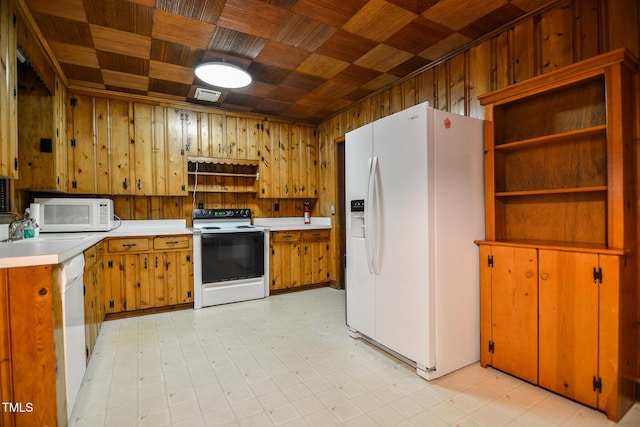 kitchen with wooden ceiling, white appliances, sink, and wooden walls