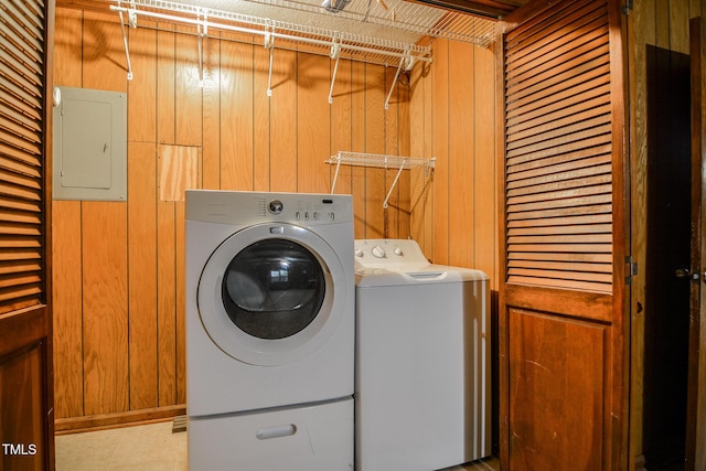 washroom featuring electric panel, wooden walls, and washer and dryer