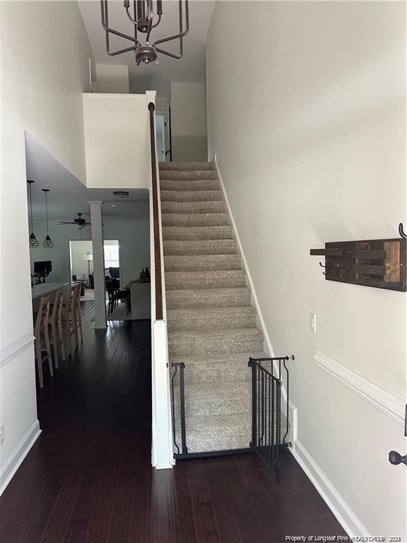 stairway with ceiling fan with notable chandelier and wood-type flooring
