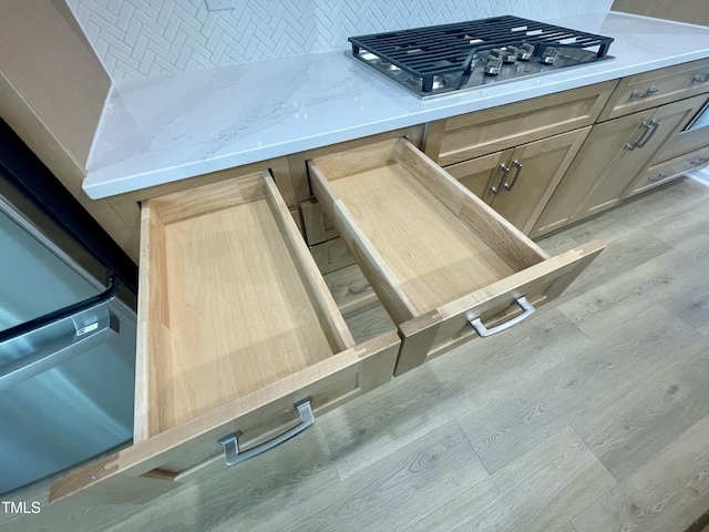 details with backsplash, stainless steel gas stovetop, and light brown cabinetry