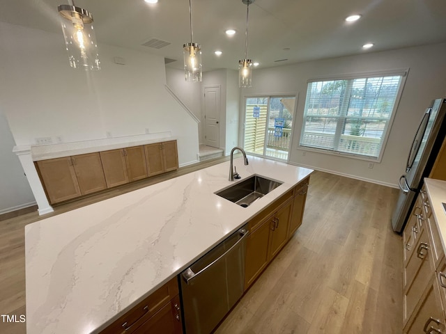 kitchen featuring light stone countertops, sink, pendant lighting, and stainless steel appliances